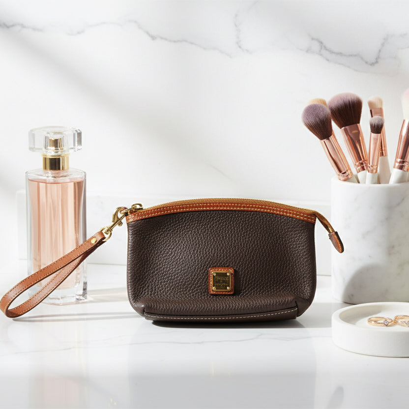 Brown leather handbag with a gold zipper and clasp on a white background