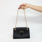 Model hand holding black designer bag by chain